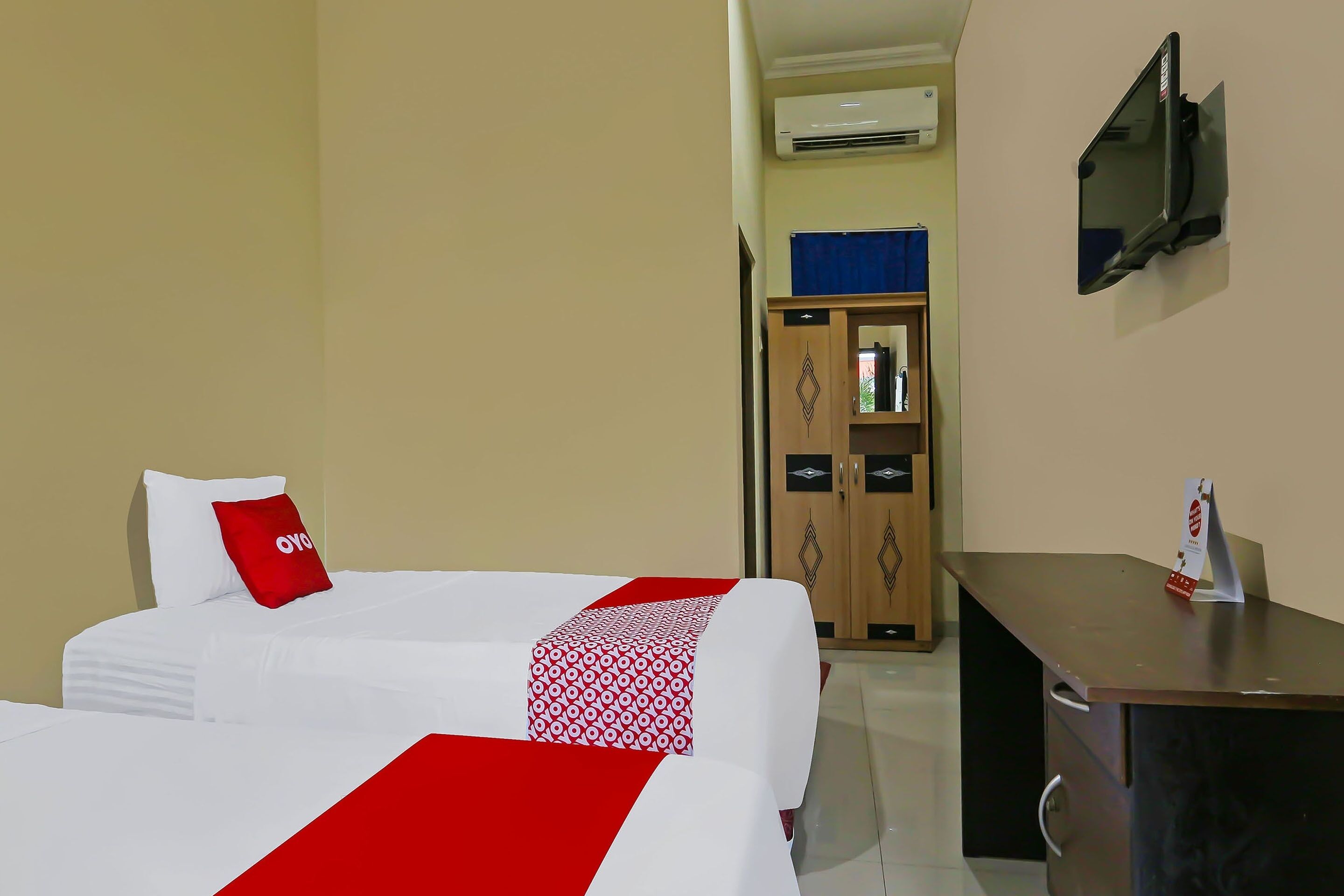 Habitación de hotel con cama, escritorio y televisor fijado a la pared.