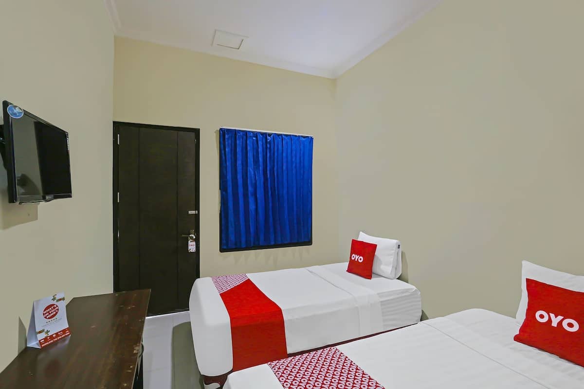 Habitación de hotel con dos camas, un televisor, una puerta y una ventana con cortinas azules.