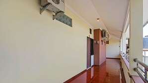 Un pasillo con piso pulido, barandilla y unidad de aire acondicionado en la pared.