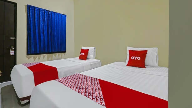 Habitación de hotel con dos camas, cada una con cubrecama rojo y blanco y almohadas a juego.
