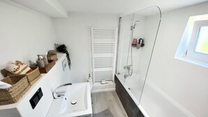 A modern bathroom with a white sink, a glass-enclosed shower, and a window above the shower. - 2 room apartment, comfortable, king size bed, TV (Hannover)