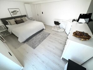 A modern bedroom with a large bed, a desk, and a chair. - Comfortable 2-room apartment with a king-size bed and TV (Hannover)