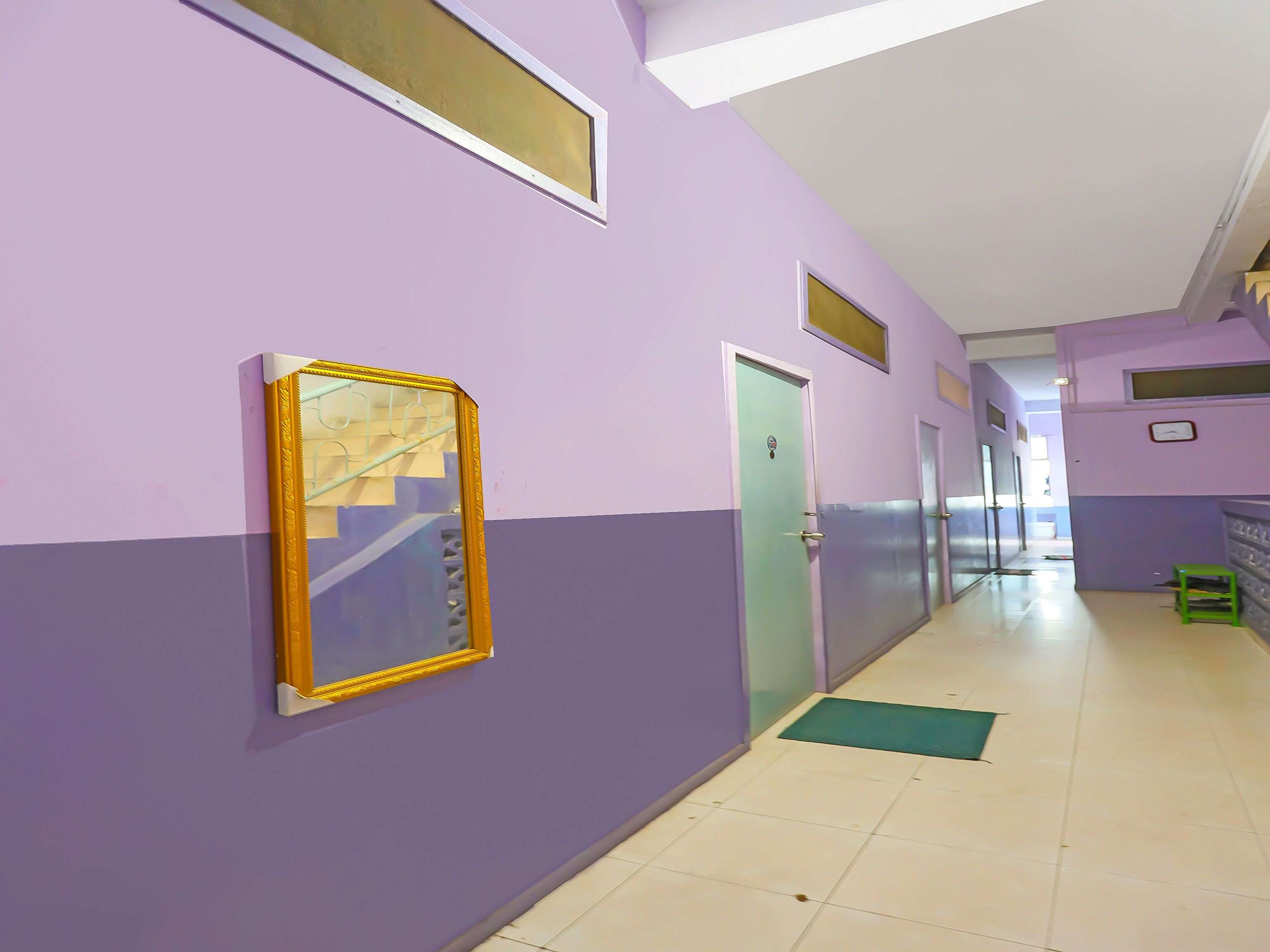 A hallway with purple walls, a green mat on the floor, and a door with a small window.