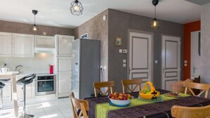 Una cocina moderna con armarios blancos, un refrigerador y un comedor con una mesa preparada para cuatro.