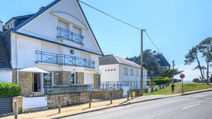 Ein zweistöckiges Gebäude mit einem Balkon, einem Steinfundament und freiem Blick auf das Meer.