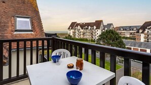 Een balkon met een tafel voor twee, met uitzicht op een woongebied met meerdere flatgebouwen.