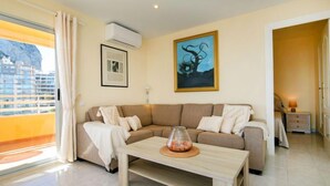 Uma sala de estar moderna com um sofá bege, uma mesa de centro de madeira e um quadro na parede.