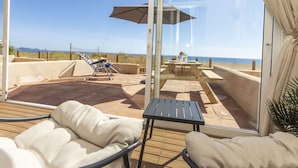 A balcony with a view of the beach, a table with a tablecloth, and lounge chairs. - Paradise beach by Interhome (Pals)