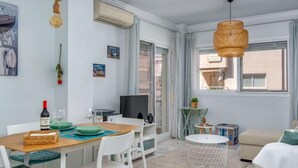 Un salon moderne comprenant un coin repas, un téléviseur et une grande fenêtre.