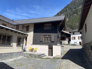 Un chalet traditionnel avec une façade en pierre, des balcons en bois et un chemin en pierre menant à l’entrée.