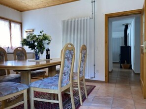 Un coin repas avec une table en bois, quatre chaises, un vase de fleurs et un radiateur.