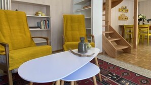 A modern living room with two yellow armchairs, a white coffee table, and a wooden staircase leading to a dining area. - Della Posta Stambecco by Interhome (Rossa)
