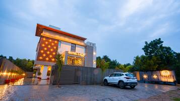 A modern hotel with a prominent sign, a paved driveway, and a parked car.