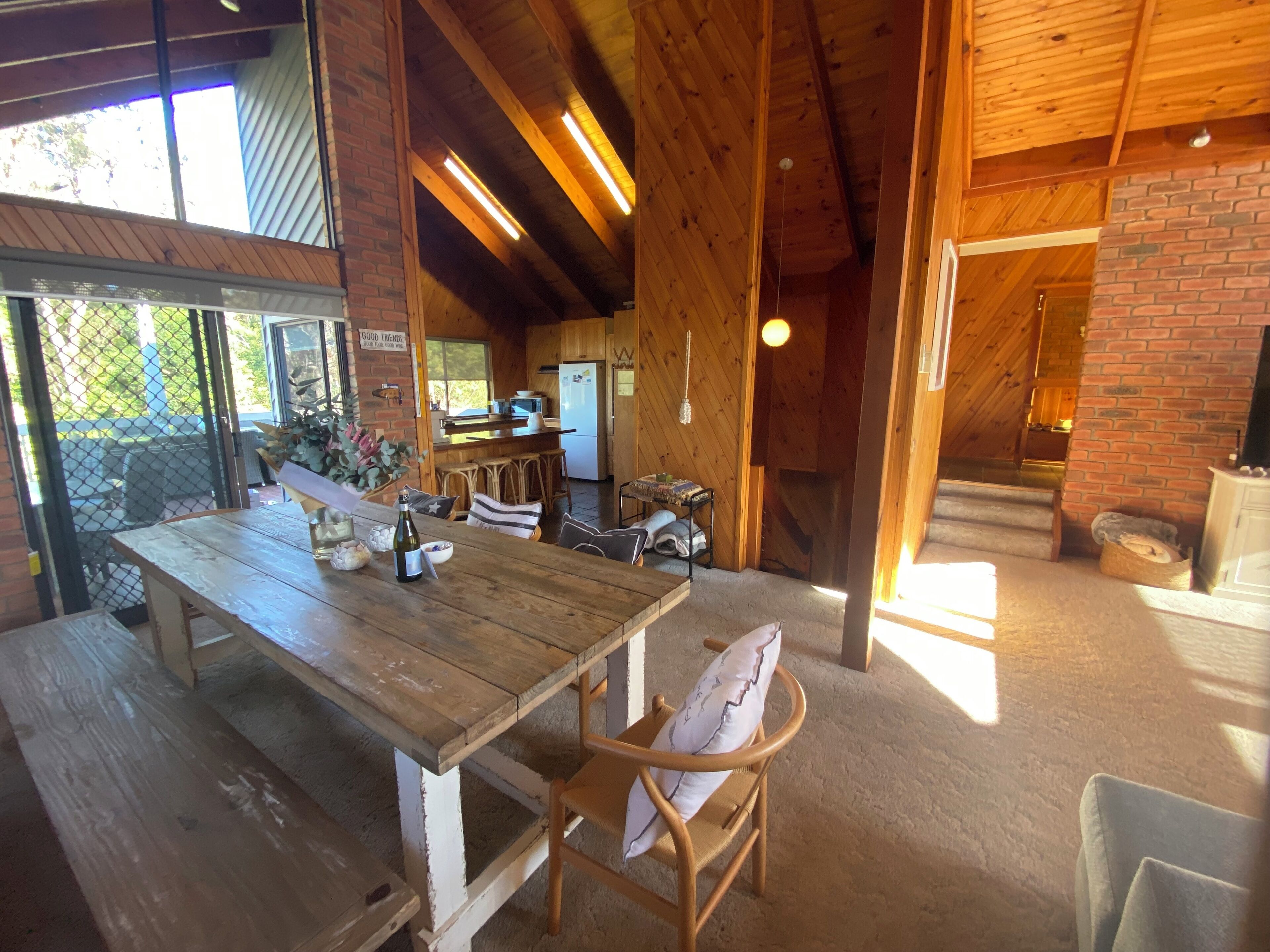 A rustic wooden interior with a dining table, chairs, and a kitchen area.