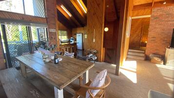 A rustic wooden interior with a dining table, chairs, and a kitchen area.