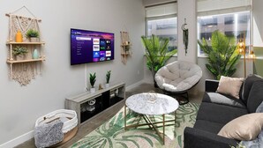 Una sala moderna con televisor de pantalla plana, asientos cómodos y plantas decorativas.
