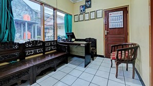 A room with a wooden bench, a desk, and a chair. There is a calendar on the wall and a door with a sign. - OYO 92406 Hotel Renata 1 (Getasan)