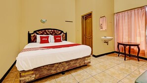 A hotel room with a bed, a bedside table, a sink, and a window with curtains. - OYO 92406 Hotel Renata 1 (Getasan)