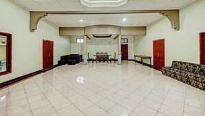 A spacious hall with a tiled floor, a central table with chairs, and red doors on the sides. - OYO 92406 Hotel Renata 1 (Getasan)