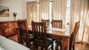 A dining area with a wooden table and chairs, a wooden cabinet, and a painting on the wall.