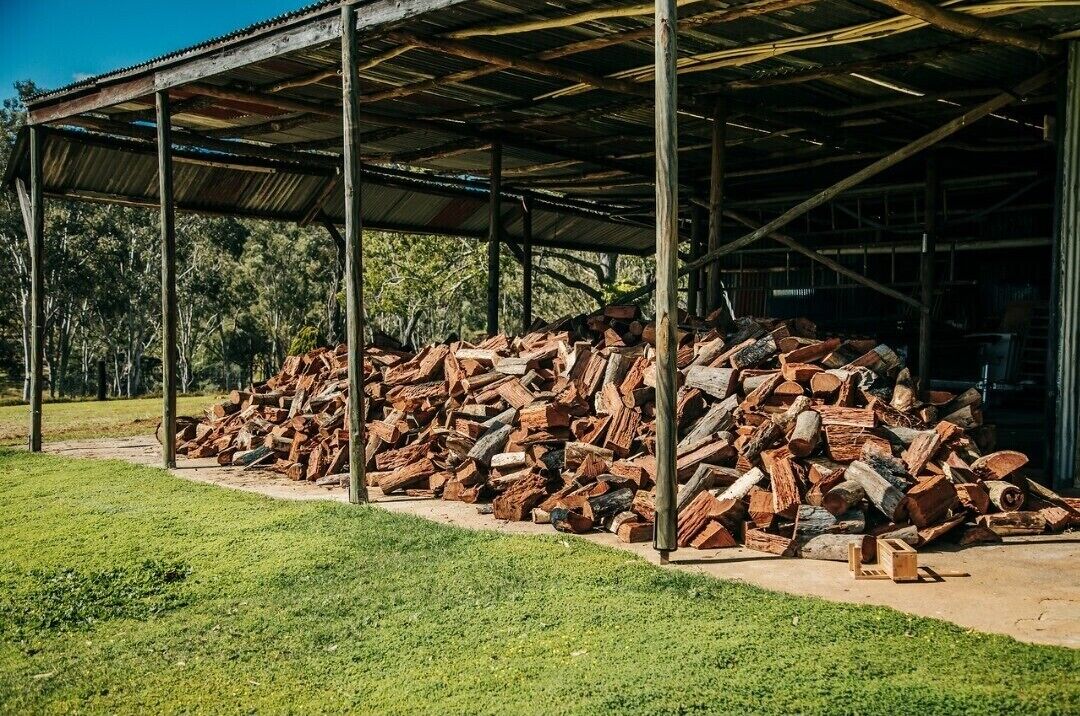 Uma área externa coberta com uma pilha de lenha sob uma estrutura de telhado de metal.