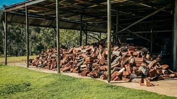 Uma área externa coberta com uma pilha de lenha sob uma estrutura de telhado de metal.