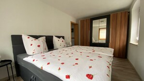 Ein Schlafzimmer mit einem Bett, einem Nachttisch, einem Spiegel und Holzboden.