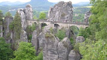Eine Steinbrücke, die Felsformationen mit einem bewaldeten Tal im Hintergrund verbindet.