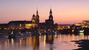 Ein historischer Gebäudekomplex mit einem markanten Turm und einer Kuppel, an einem Fluss mit Booten gelegen.
