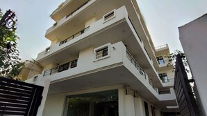 Un edificio residencial de varios pisos con techo plano, varios balcones y una entrada con portón.