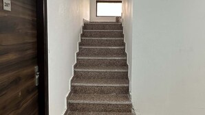 Una escalera con una puerta de madera a la izquierda y un ventanal en la parte superior.