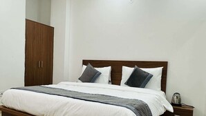 Un dormitorio con una cama de madera, ropa de cama blanca y una mesita de noche con un hervidor.