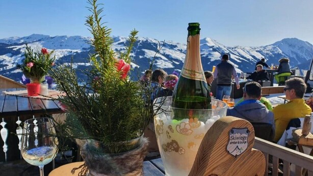 A table with a bottle of champagne, a glass of wine, and a wooden sign with the word "Reservation".