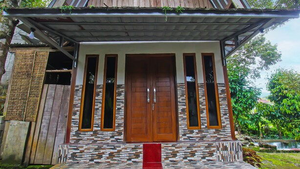 A house with a wooden facade, a tiled entrance, and a red carpet leading to the door.
