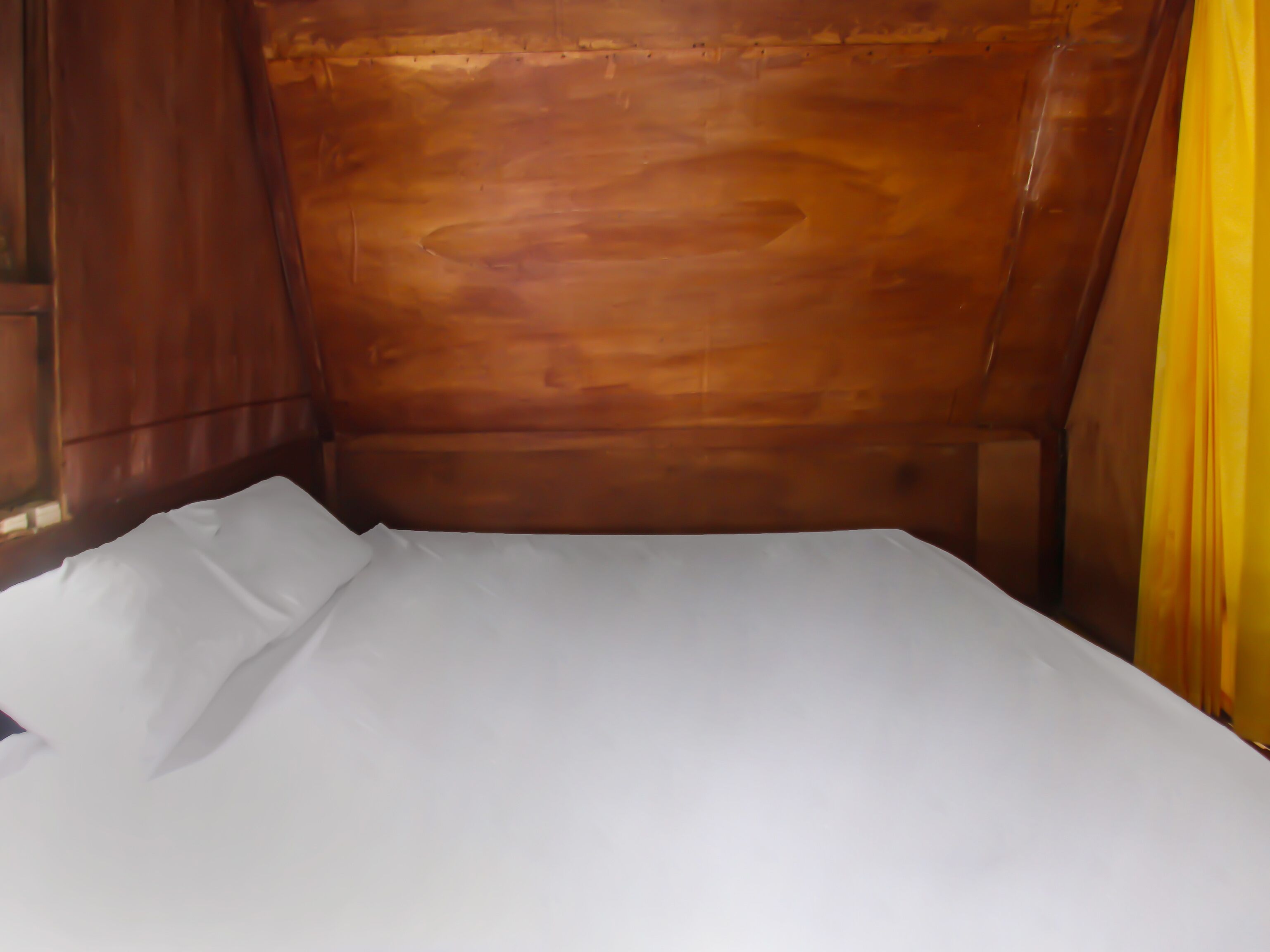 A wooden headboard bed with white linens.