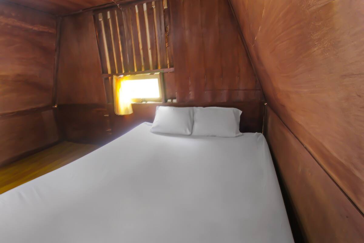 Un lit simple dans une pièce aux murs en bois et dotée d’une fenêtre.