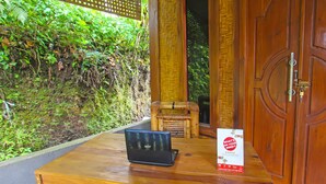 A wooden table with a laptop and a sign, a wooden door, and a wall with greenery.
