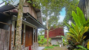 A traditional wooden house with a tiled porch and a small garden area.