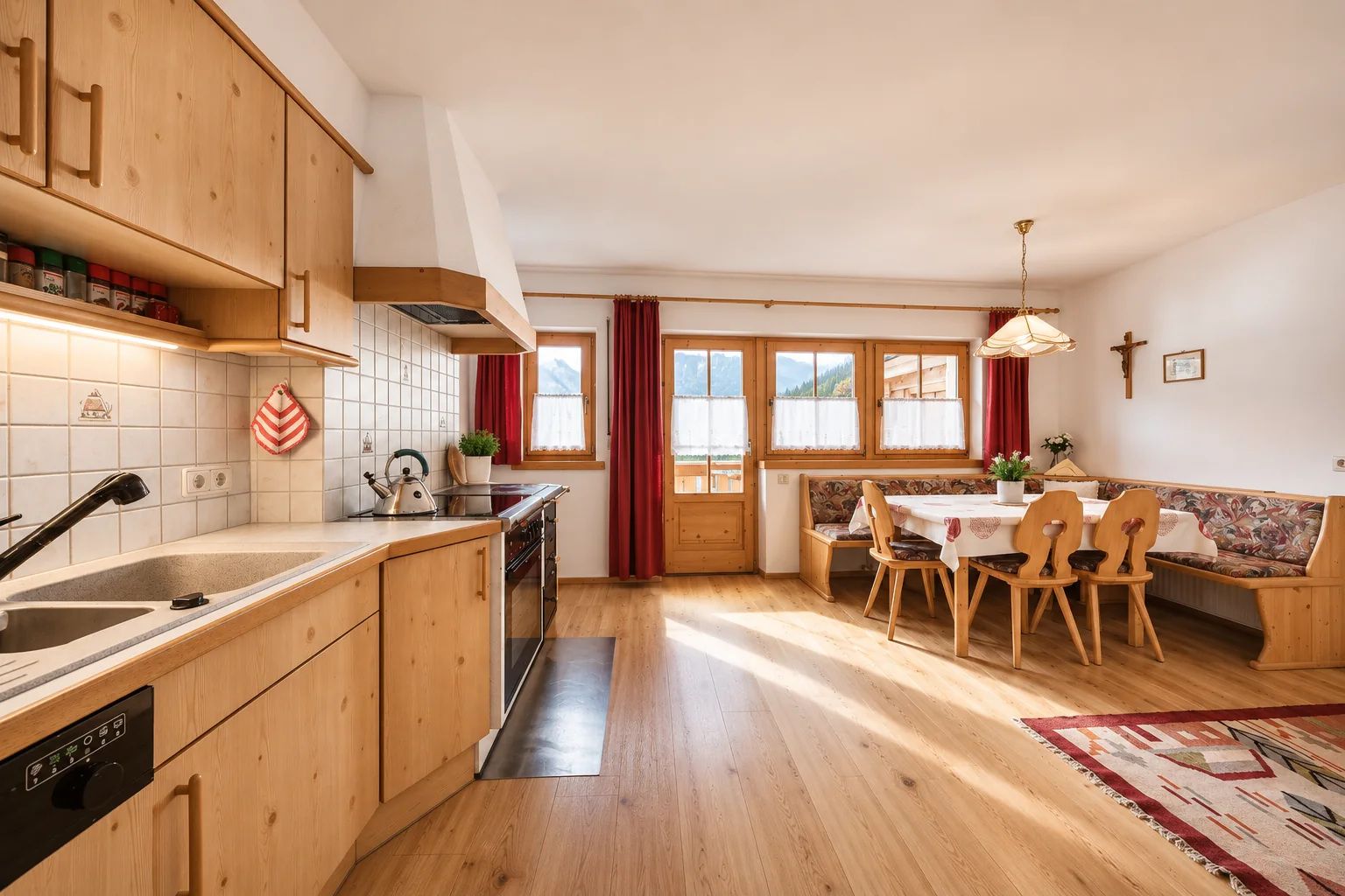 Une cuisine avec des meubles de rangement en bois, une cuisinière et un coin repas comprenant une table et des chaises.