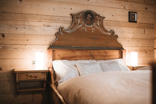 Un lit en bois avec une tête de lit sculptée, deux tables de chevet et une petite table de nuit.