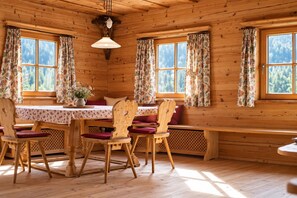 L’intérieur d’un chalet en bois, avec une table à manger, des chaises et un banc.