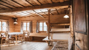 Eine rustikale Holzhütte mit Essbereich, einer Bank und einem Bett.