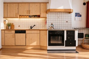 Una cocina con armarios de madera, lavavajillas integrado, estufa y salpicadero de azulejos.