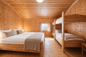 Une cabane en bois avec des lits superposés, une fenêtre avec des rideaux et un plancher en bois.