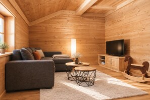 Un interior de madera acogedor con un sofá, televisor y un caballo balancín.