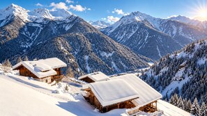 A mountain cabin with a wooden exterior and snow-covered roof, surrounded by snow-covered trees and mountains. - Chalet Ulten (Santa Valburga)
