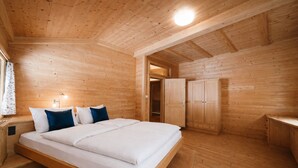 Ein Schlafzimmer einer Holzhütte mit einem Bett, Nachttischen und einem Kleiderschrank.
