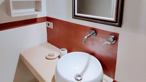 A bathroom with a white sink, a mirror, and a red-tiled wall. - MASSERIA TENUTA SOFIA (Otranto)