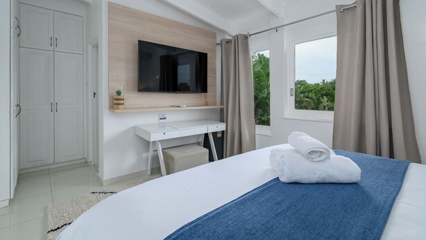 A modern bedroom with a bed, a desk, a TV, and a window with curtains. - San Lameer Villa 3309 (Southbroom)