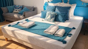 Ein ordentlich bezogenes Bett mit blauer und weißer Bettwäsche, einem blauen Kopfteil und einer passenden blauen Decke.